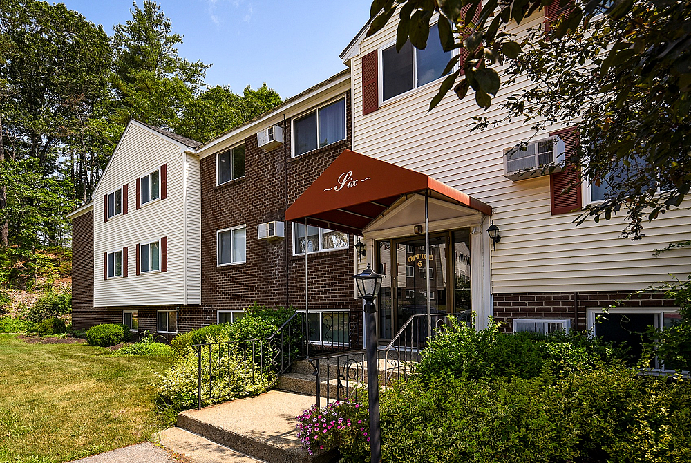Charming apartment exterior with a welcoming entrance, surrounded by lush greenery in a serene setting.