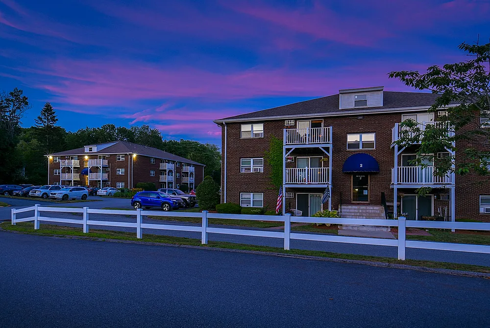 Charming apartment complex at dusk, featuring inviting balconies and serene surroundings with a vibrant sunset sky.