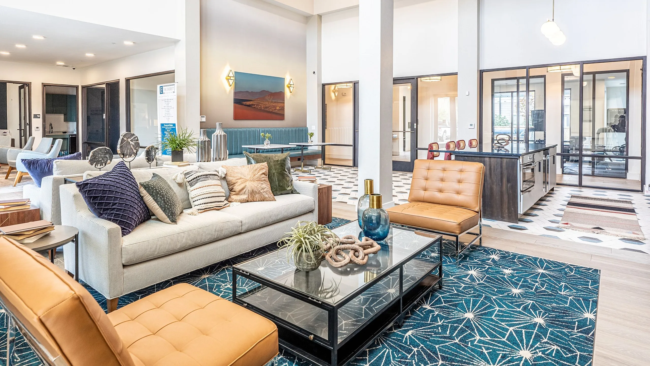 Elegant and spacious open-plan living area with contemporary decor, featuring stylish furniture, vibrant artwork, and glass partitions for a modern touch.