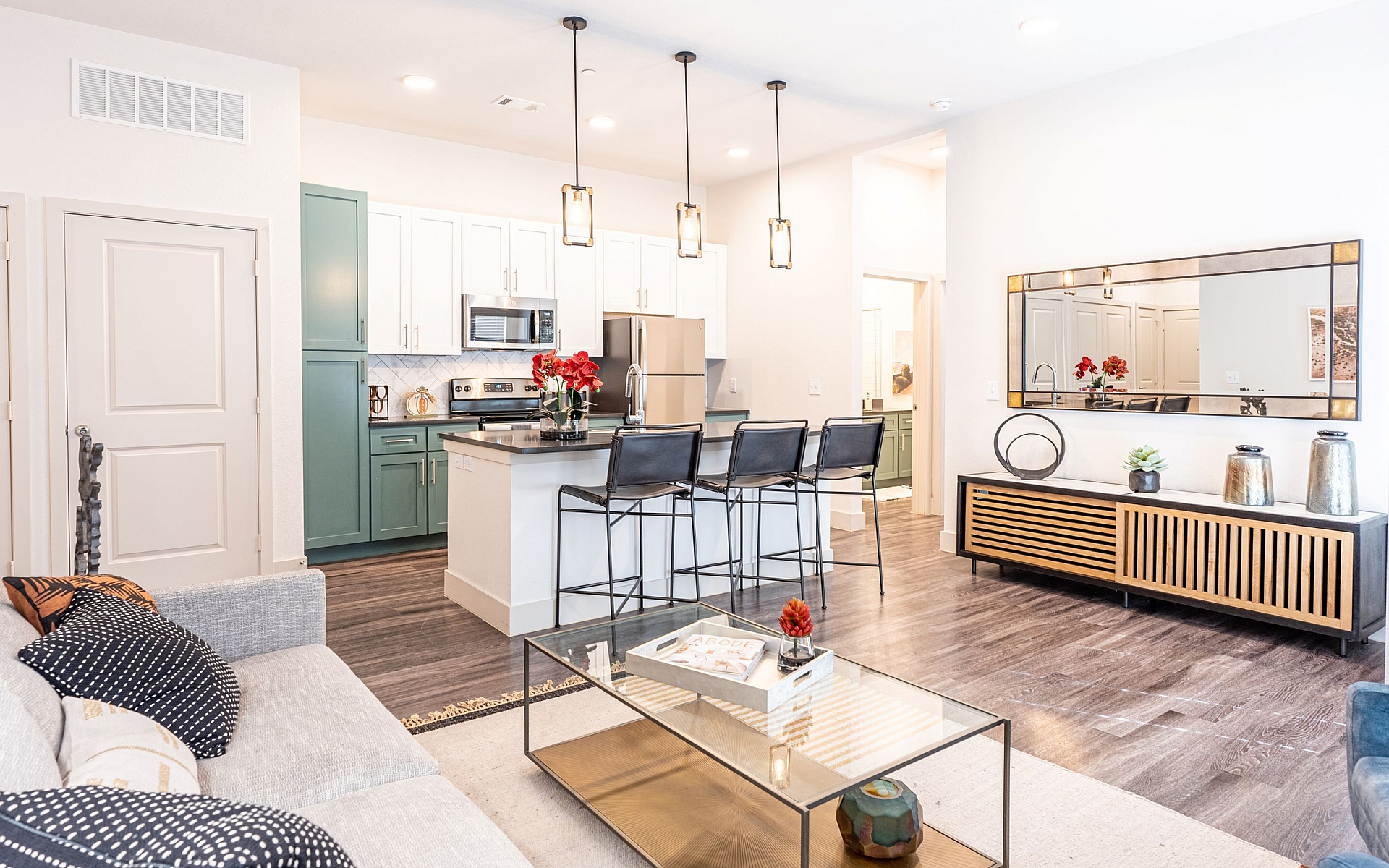 Modern open-concept living area with a sleek kitchen, stylish island seating, cozy grey sofa, and elegant decor.
