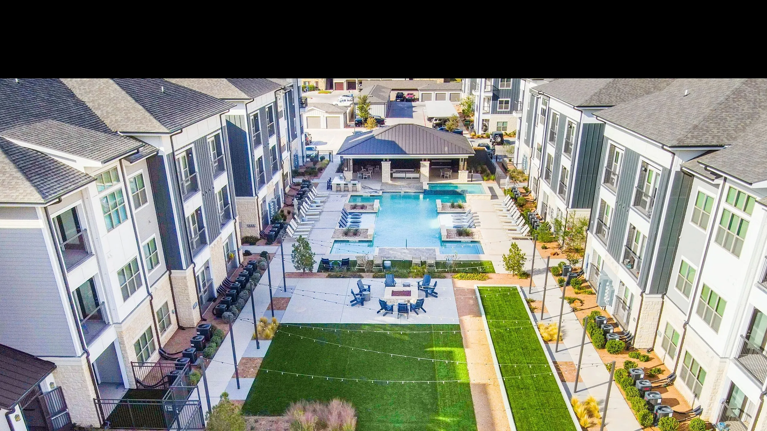 Modern apartment complex featuring a luxurious swimming pool, spacious sun deck, and beautifully landscaped courtyard.