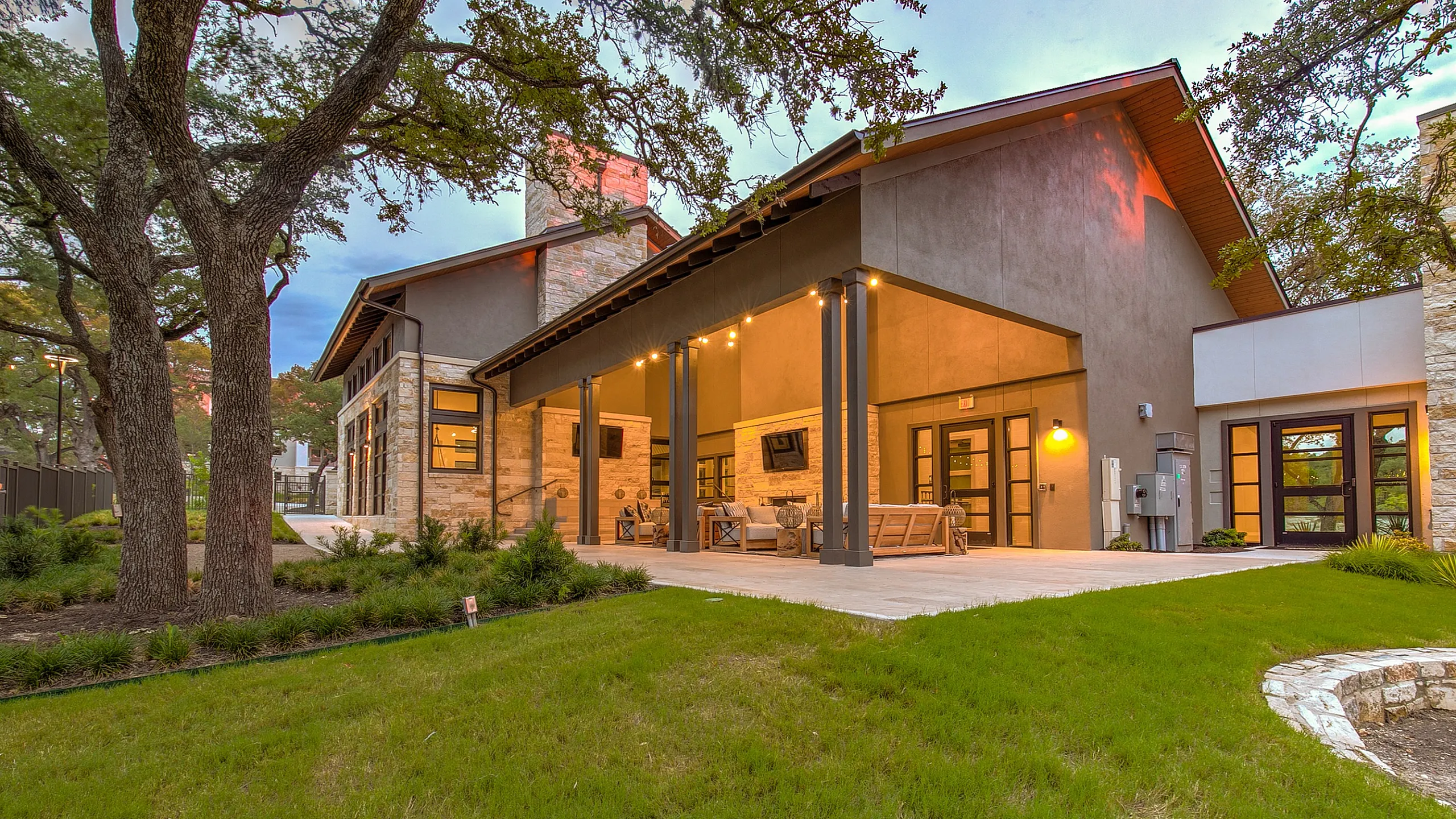 Charming outdoor patio with modern lighting and lush green lawn, perfect for relaxation and entertaining.
