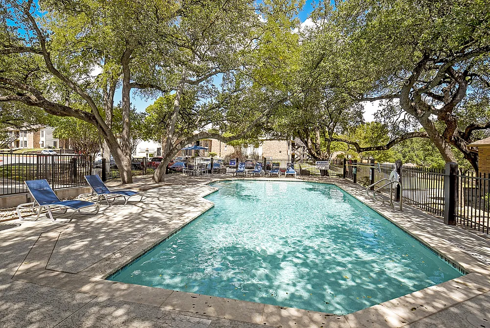 Inviting outdoor pool area surrounded by lush trees and comfortable lounge chairs, perfect for relaxation and leisure.