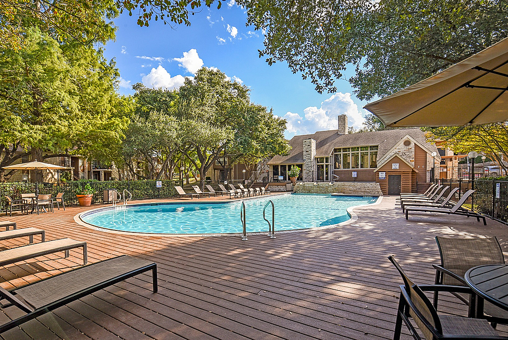 Charming outdoor pool area surrounded by lush trees and modern lounge seating, perfect for relaxing and enjoying the serene environment.