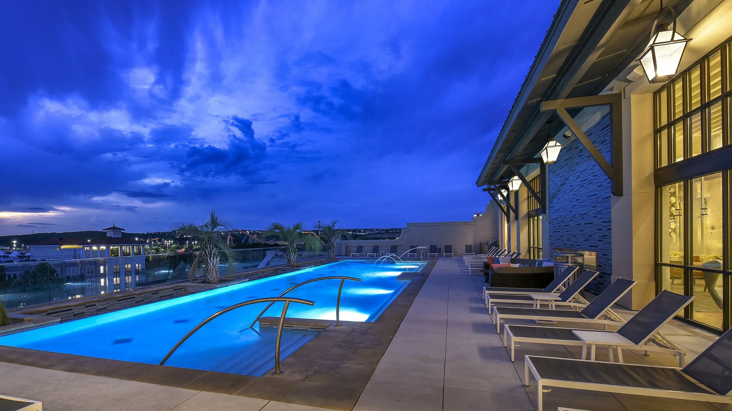 Elegant rooftop pool with modern lounge chairs and stunning evening sky view.
