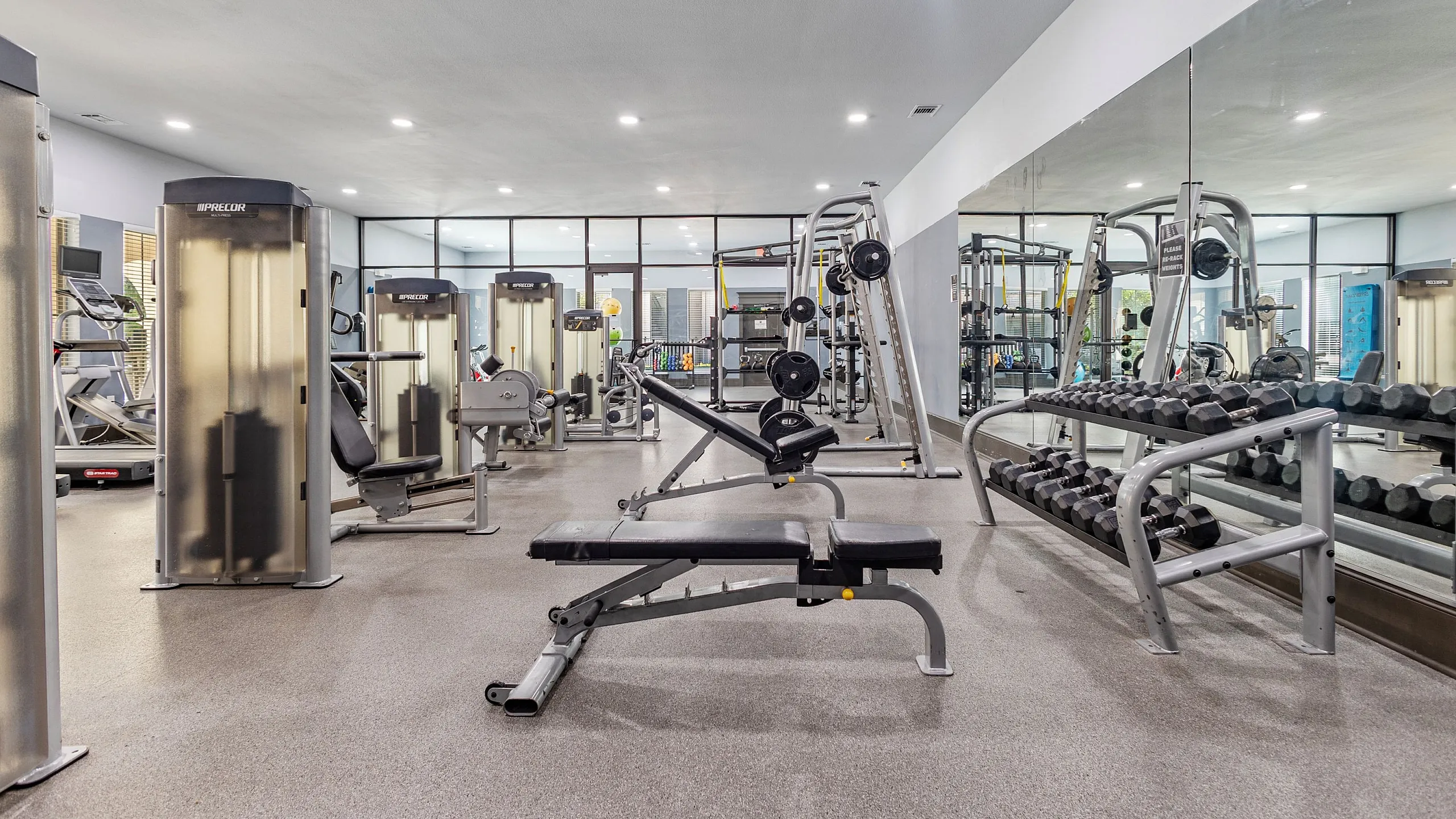 Modern gym with state-of-the-art fitness equipment, mirrors, and ample lighting for an energizing workout experience.