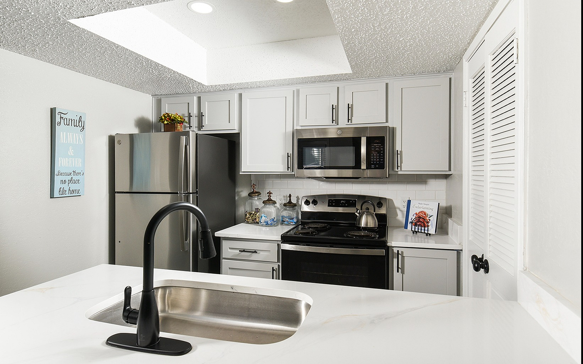 Modern kitchen with sleek white cabinetry, stainless steel appliances, and elegant black fixtures. Bright and inviting space perfect for culinary adventures.