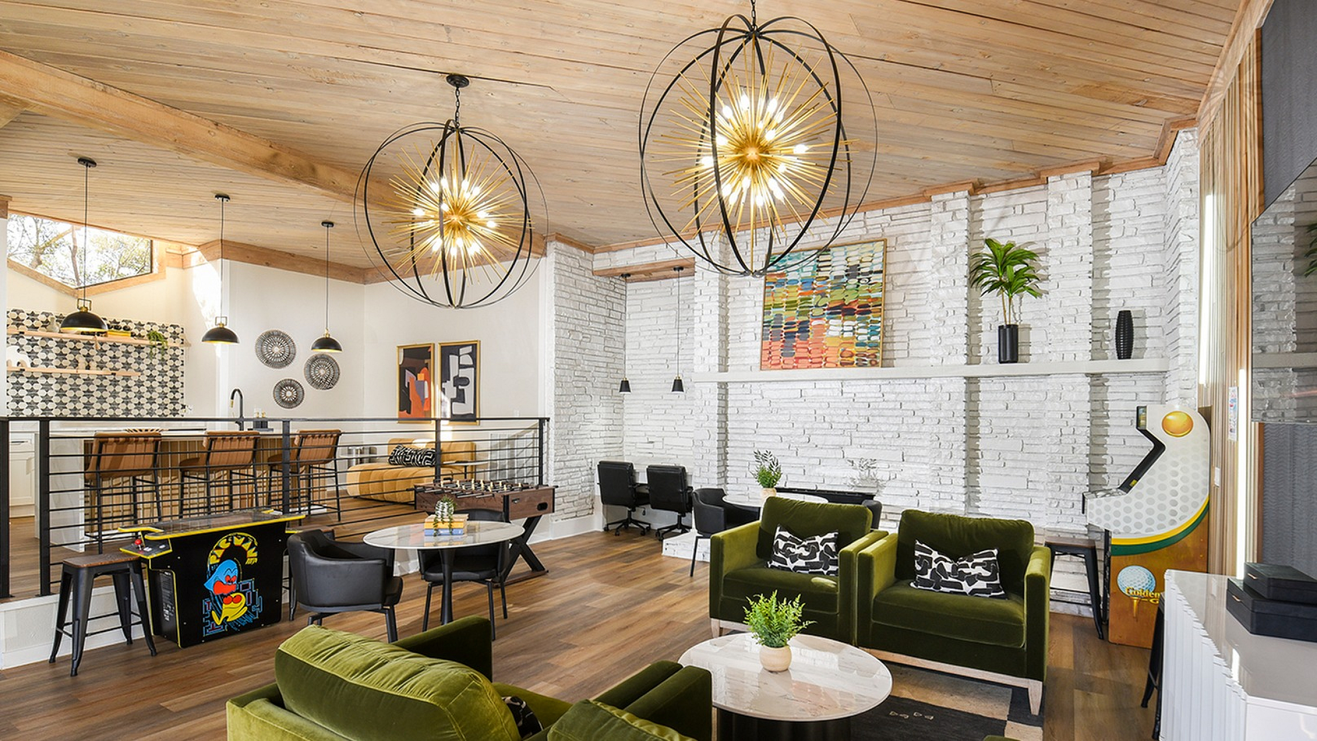 Chic open-concept living space featuring plush green velvet seating, contemporary lighting, and a stylish kitchen with bar seating.