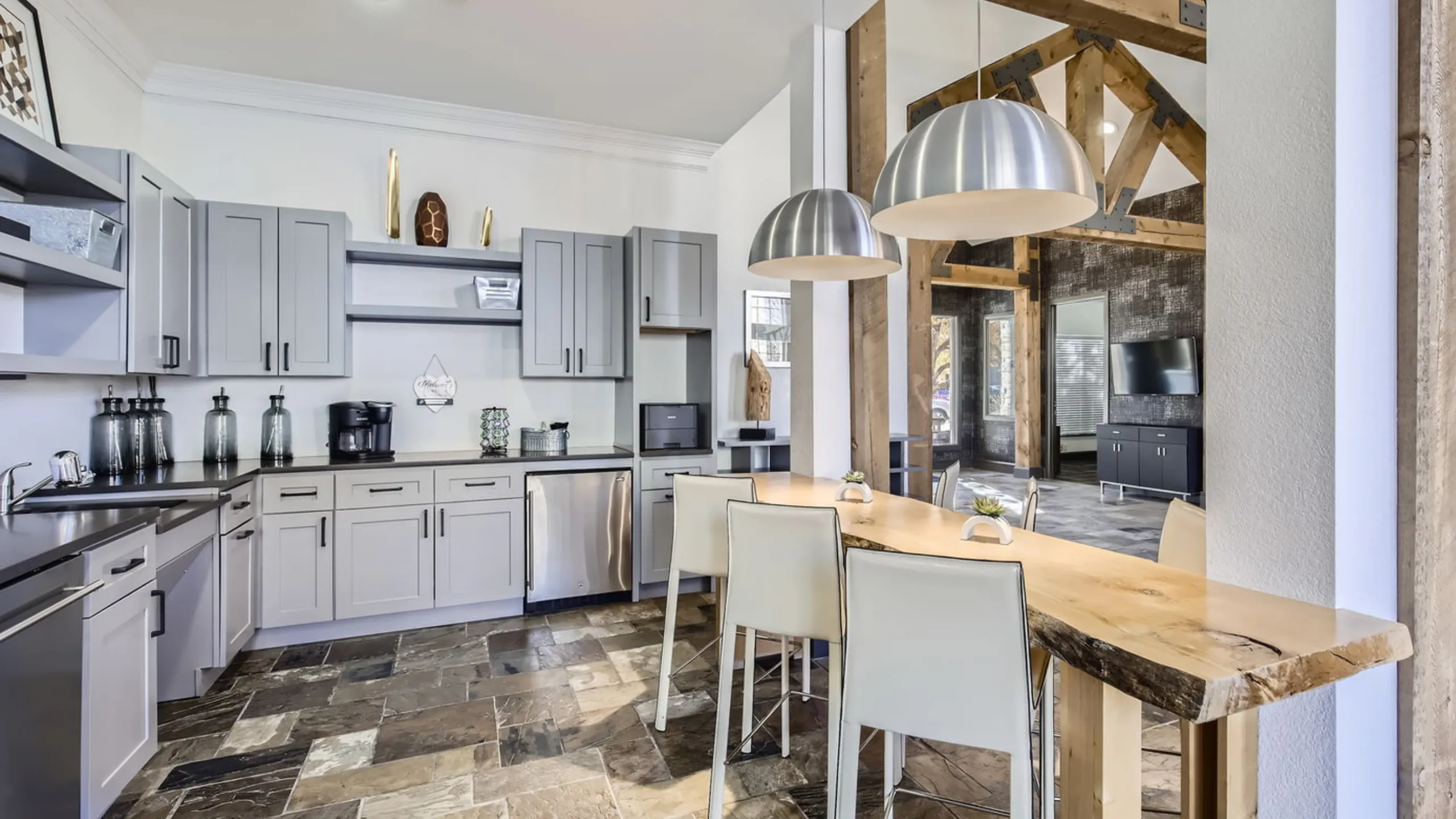 Spacious modern clubhouse kitchen with elegant gray cabinets, wooden accents, and sleek pendant lighting.