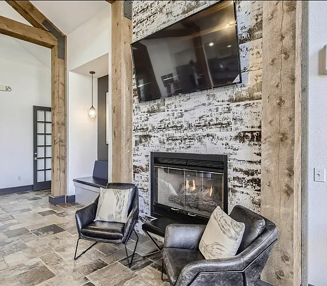 Modern lounge area with leather chairs, fireplace, and mounted TV