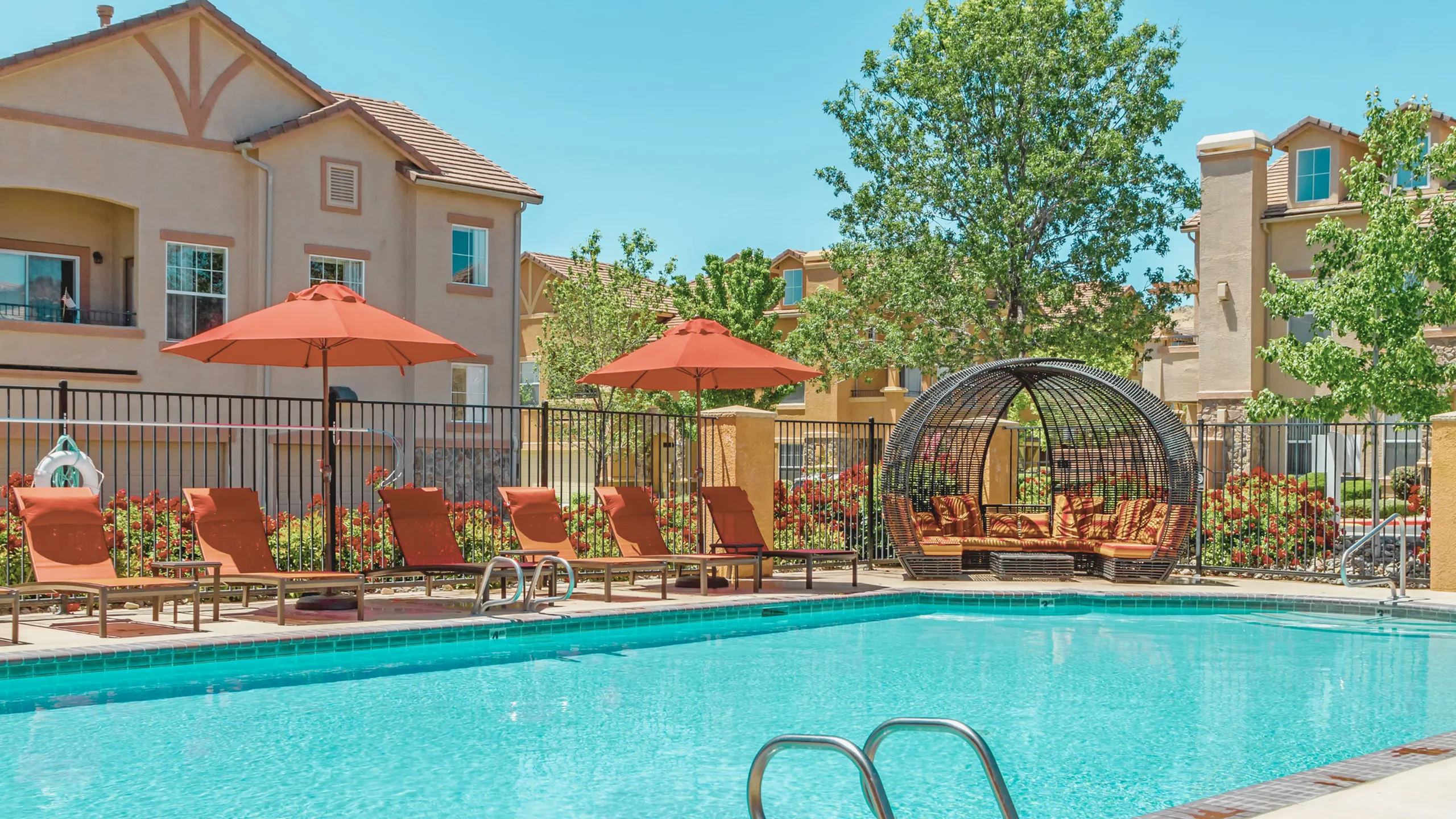 Relaxing poolside area at luxury apartment complex with loungers and umbrellas