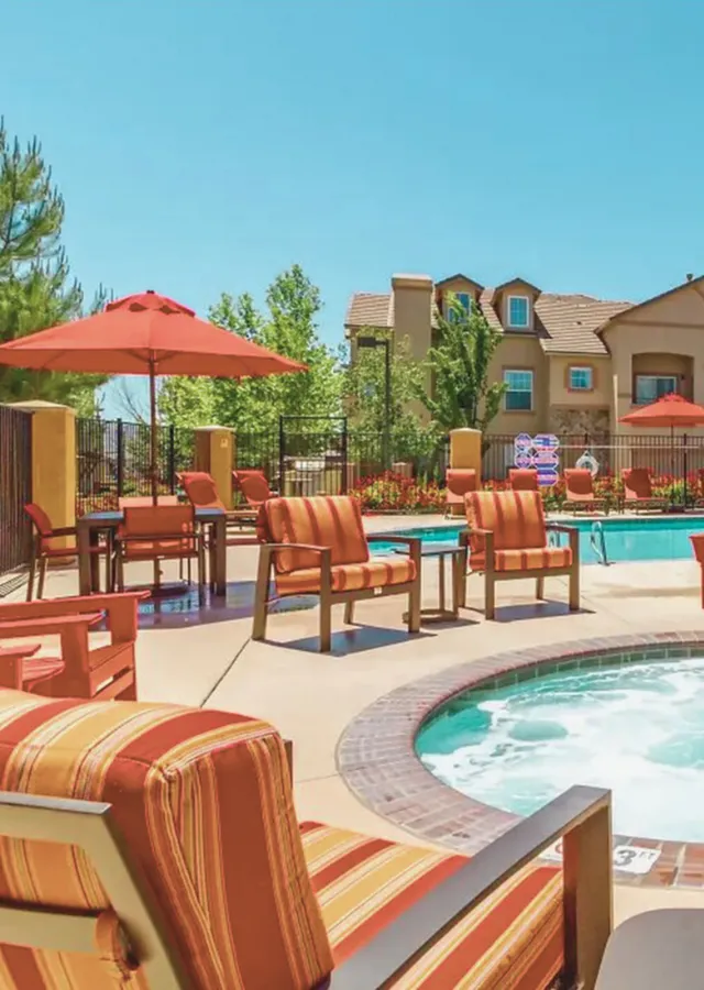 Sunny poolside area with colorful furniture and vibrant umbrellas.