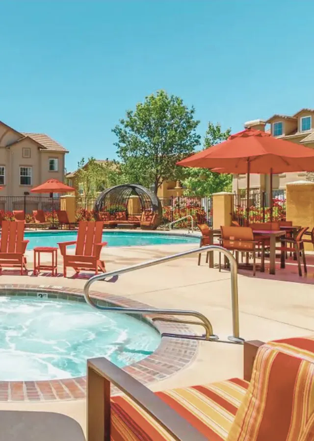 Vibrant poolside area with cozy lounging chairs and a pristine swimming pool under a clear blue sky.