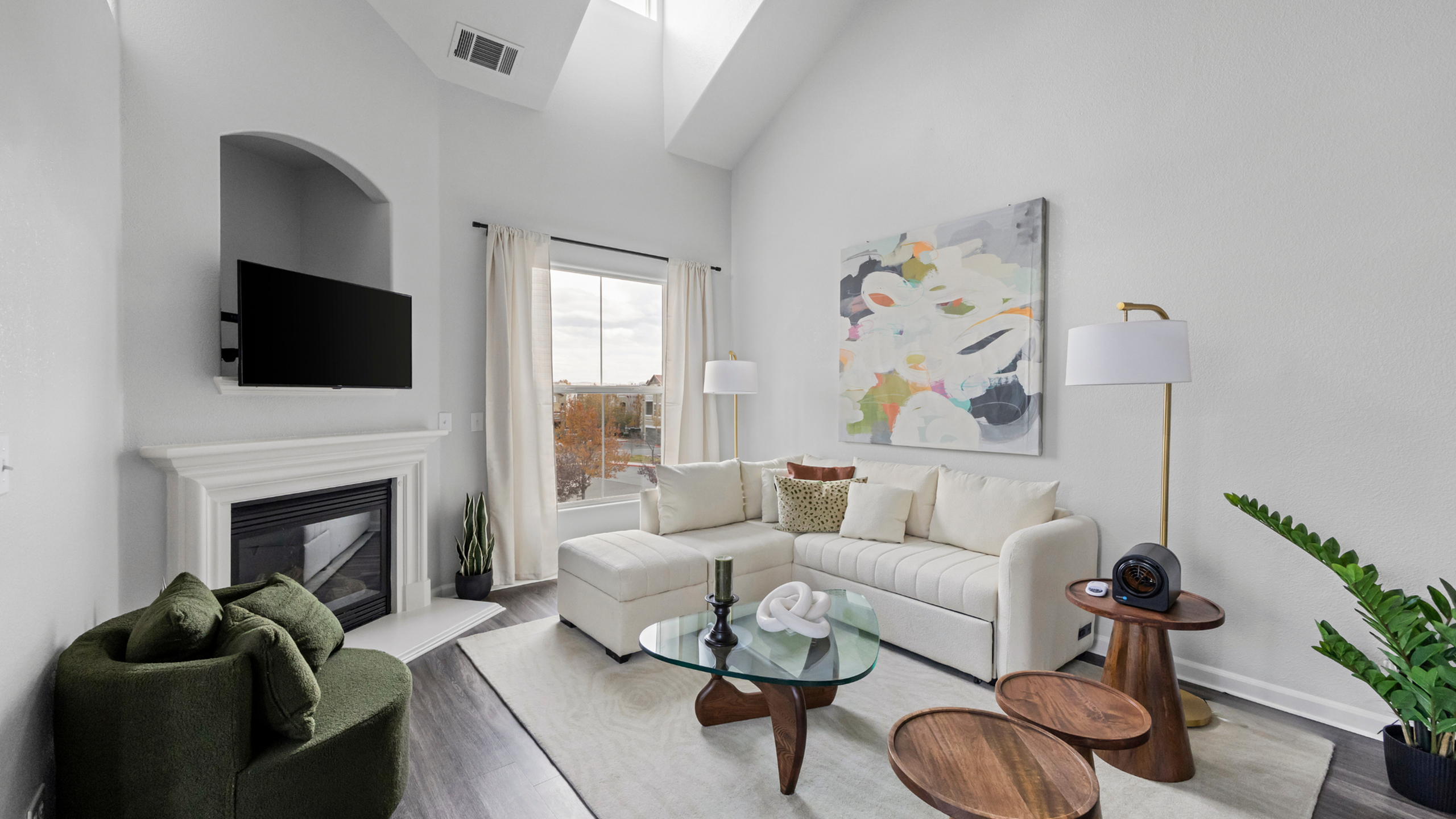Bright and modern living room with sectional sofa, abstract art, and a cozy fireplace.