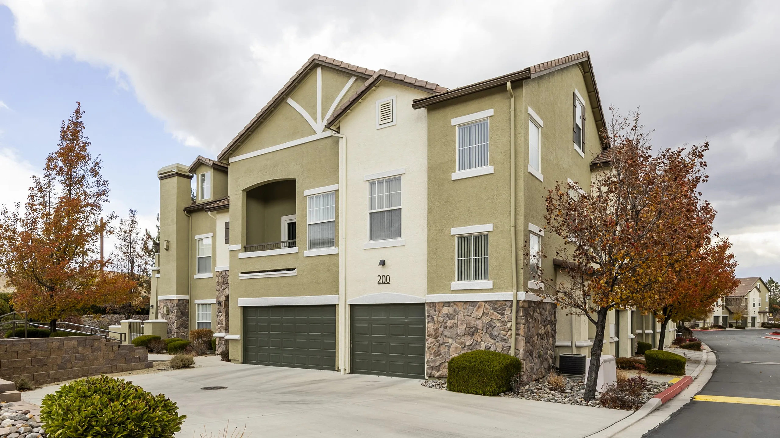 Stunning two-story suburban apartment with stone accents and lush landscaping.