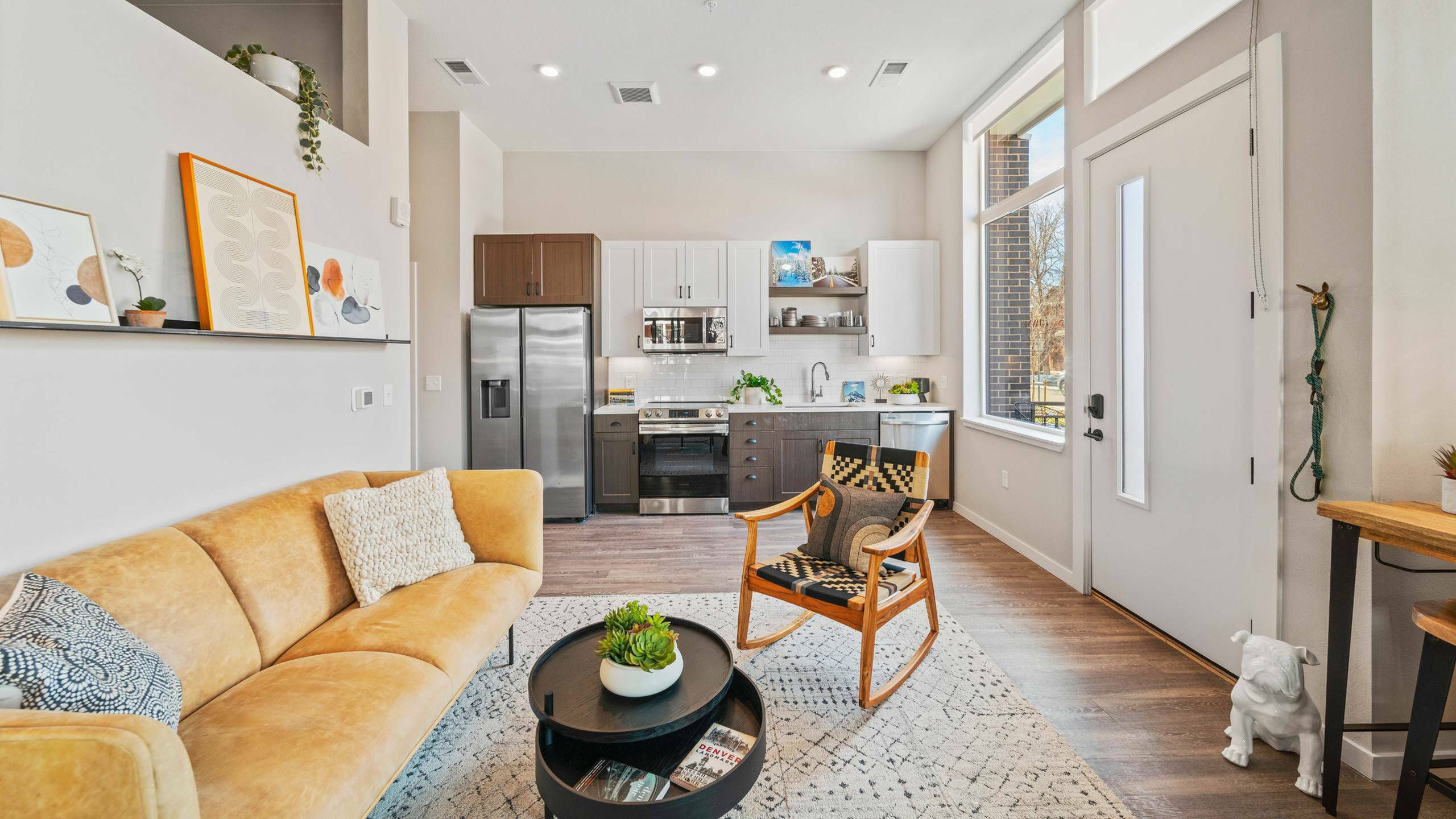 Bright and stylish open-concept apartment with a cozy living room, modern kitchen, and artistic decor.