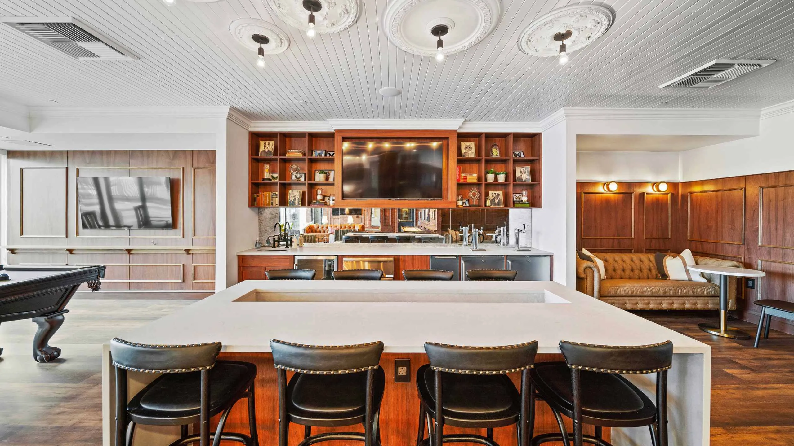 Elegant entertainment room with a modern bar, seating area, and pool table.