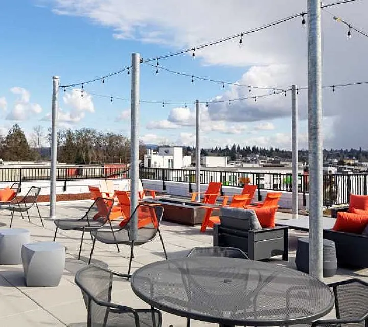 Chic rooftop terrace with stylish seating and string lights, overlooking a scenic urban view.