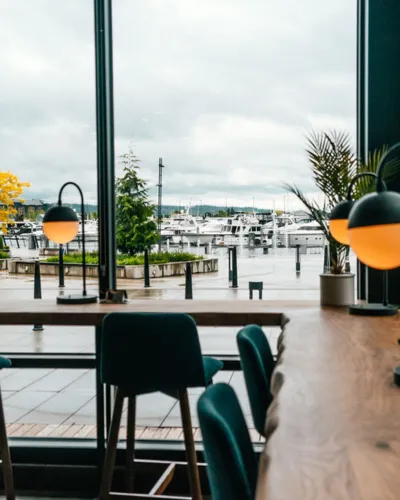 Chic dining area with large windows overlooking a marina filled with boats.