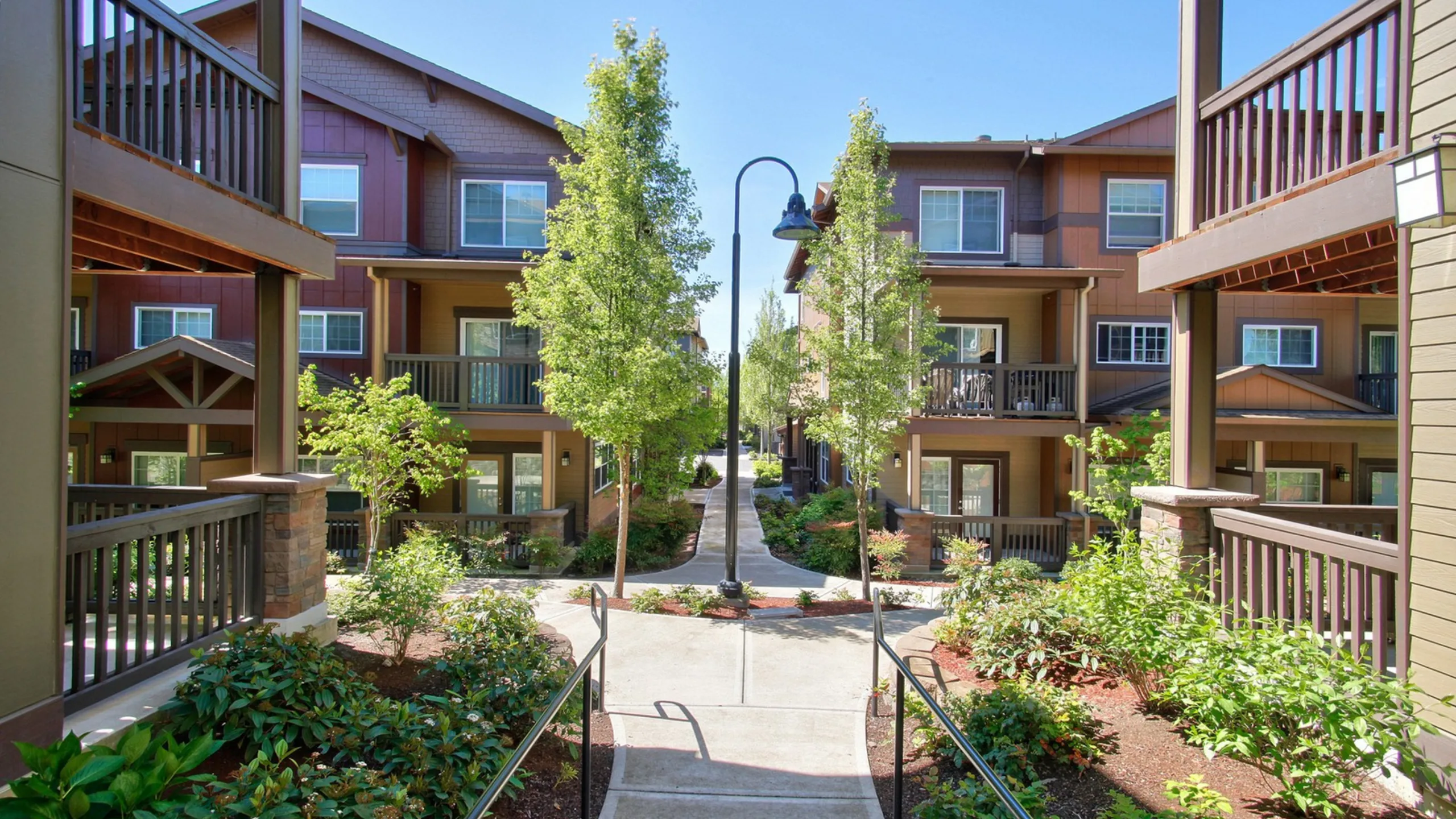 Lush courtyard surrounded by modern apartment buildings with balconies and greenery.