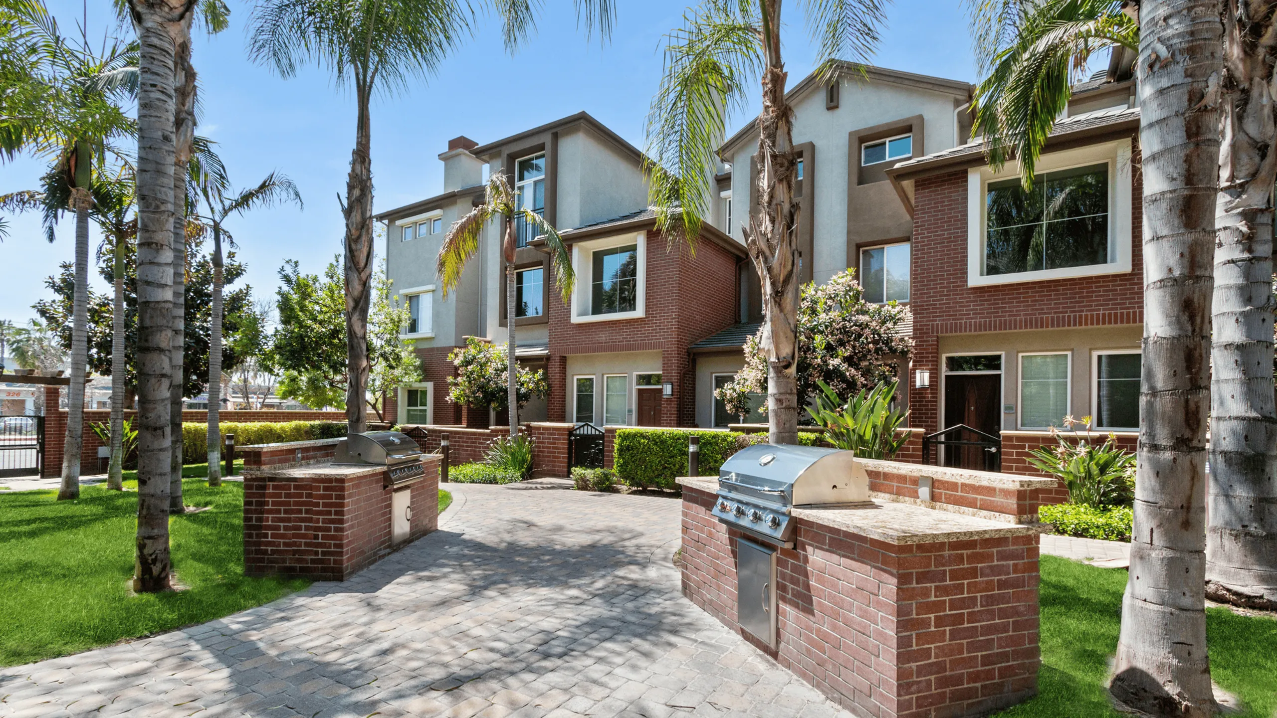 Charming apartment exterior with lush palm trees and outdoor grill area, perfect for enjoying sunny days.