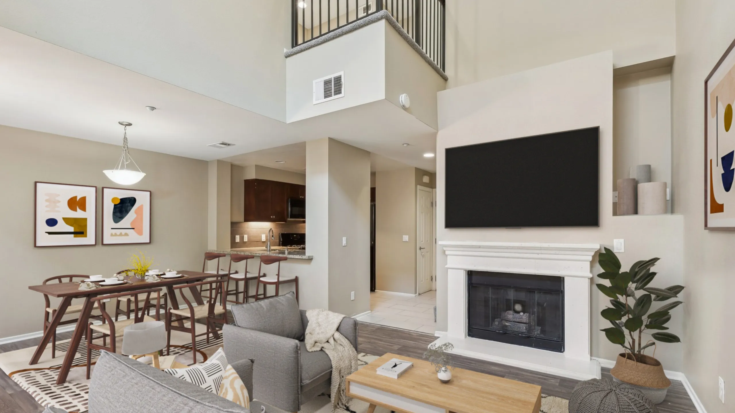 Inviting open-concept living room with a cozy fireplace, modern dining area, and sleek kitchen, highlighted by elegant art and sophisticated decor.
