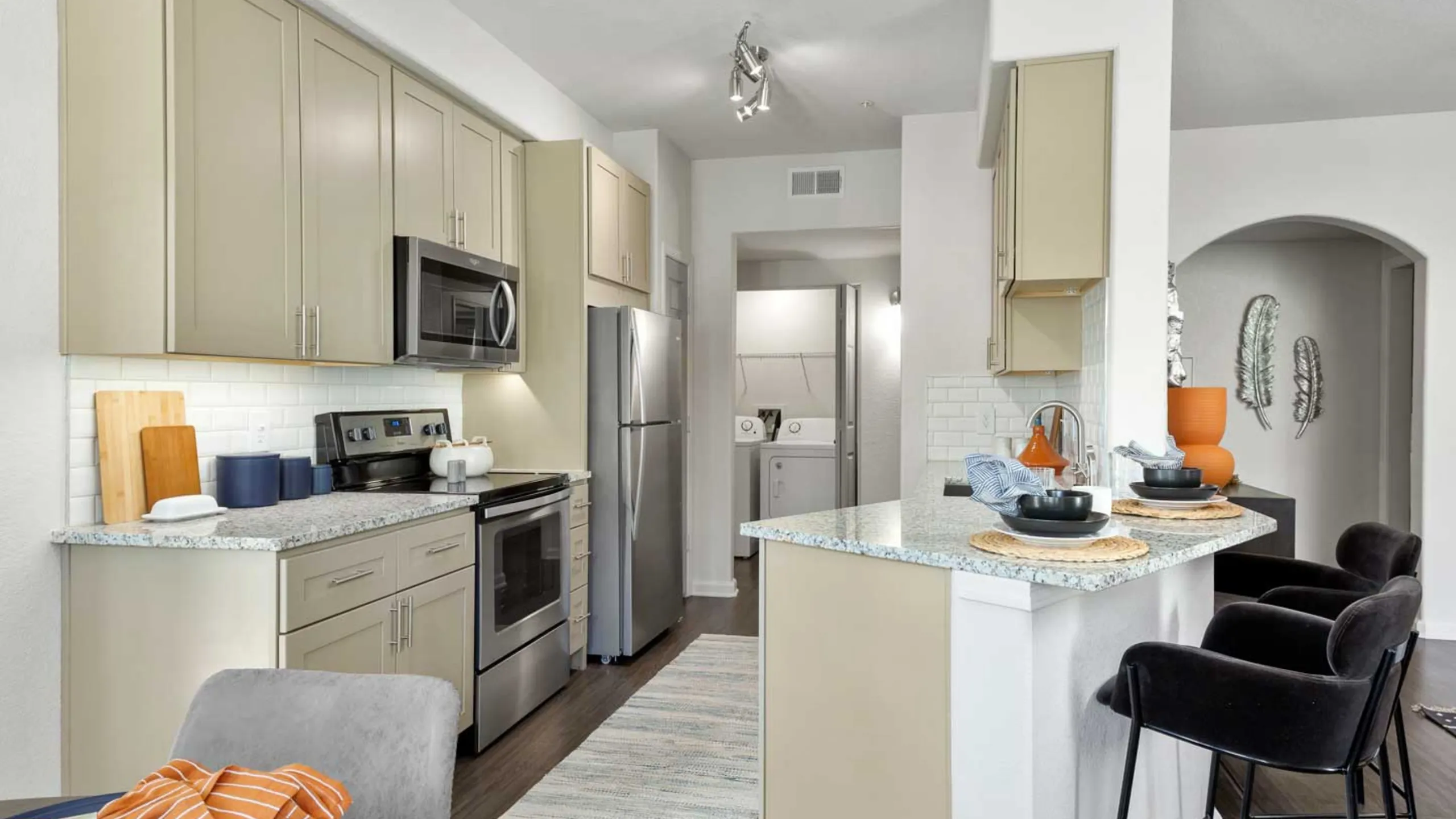 Bright and modern kitchen with sleek stainless steel appliances, elegant cabinetry, and a cozy breakfast bar seating area.