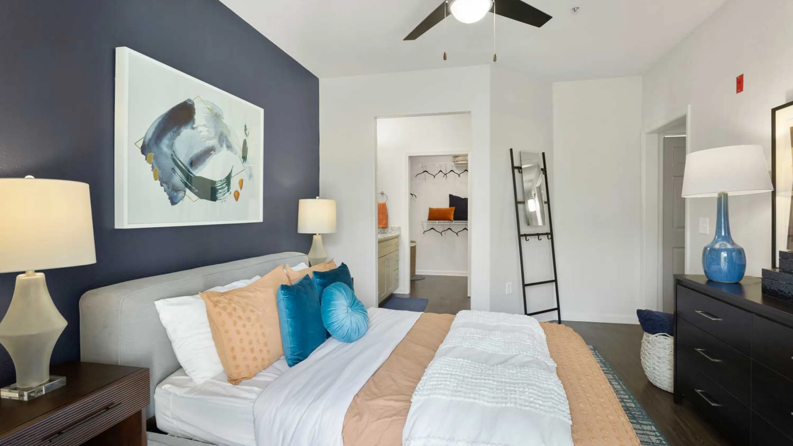 Luxurious bedroom with plush bedding, elegant artwork, and spacious walk-in closet.