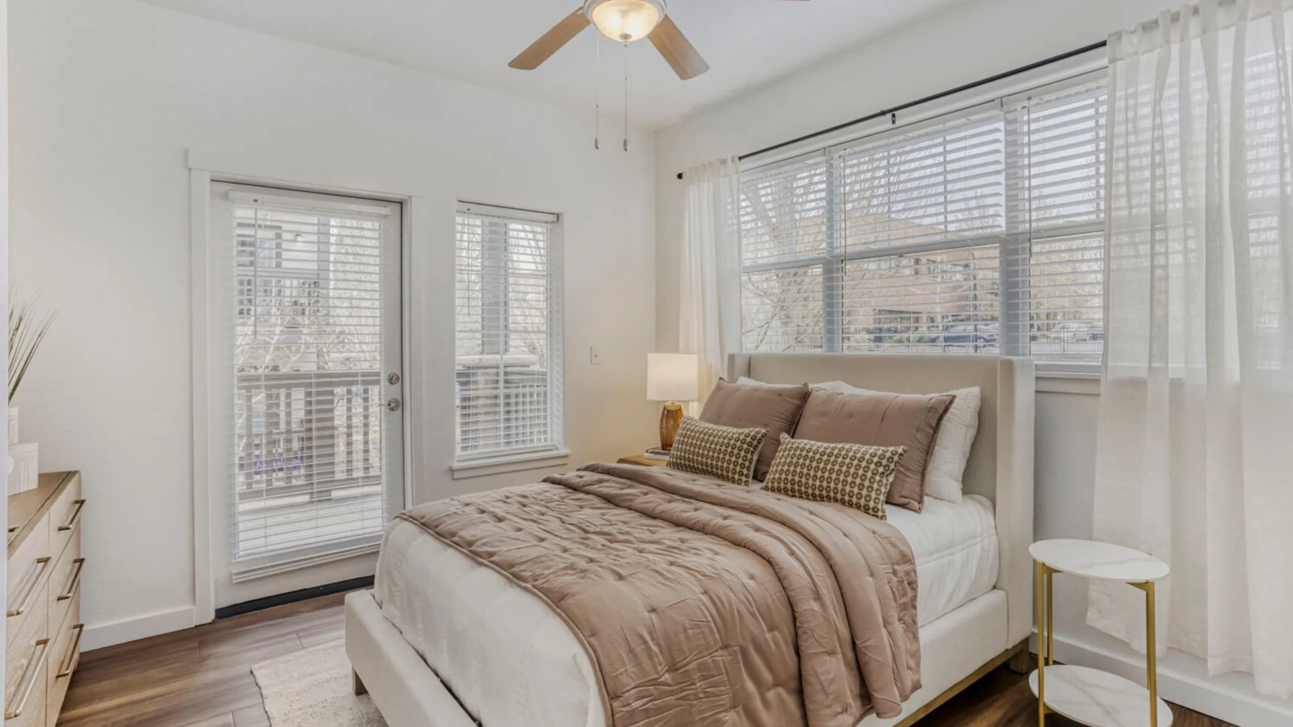Bright and airy bedroom with stylish decor, featuring large windows and access to a private balcony.