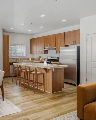 Contemporary kitchen boasting sleek stainless steel appliances, elegant wood cabinetry, and a cozy breakfast bar with seating.