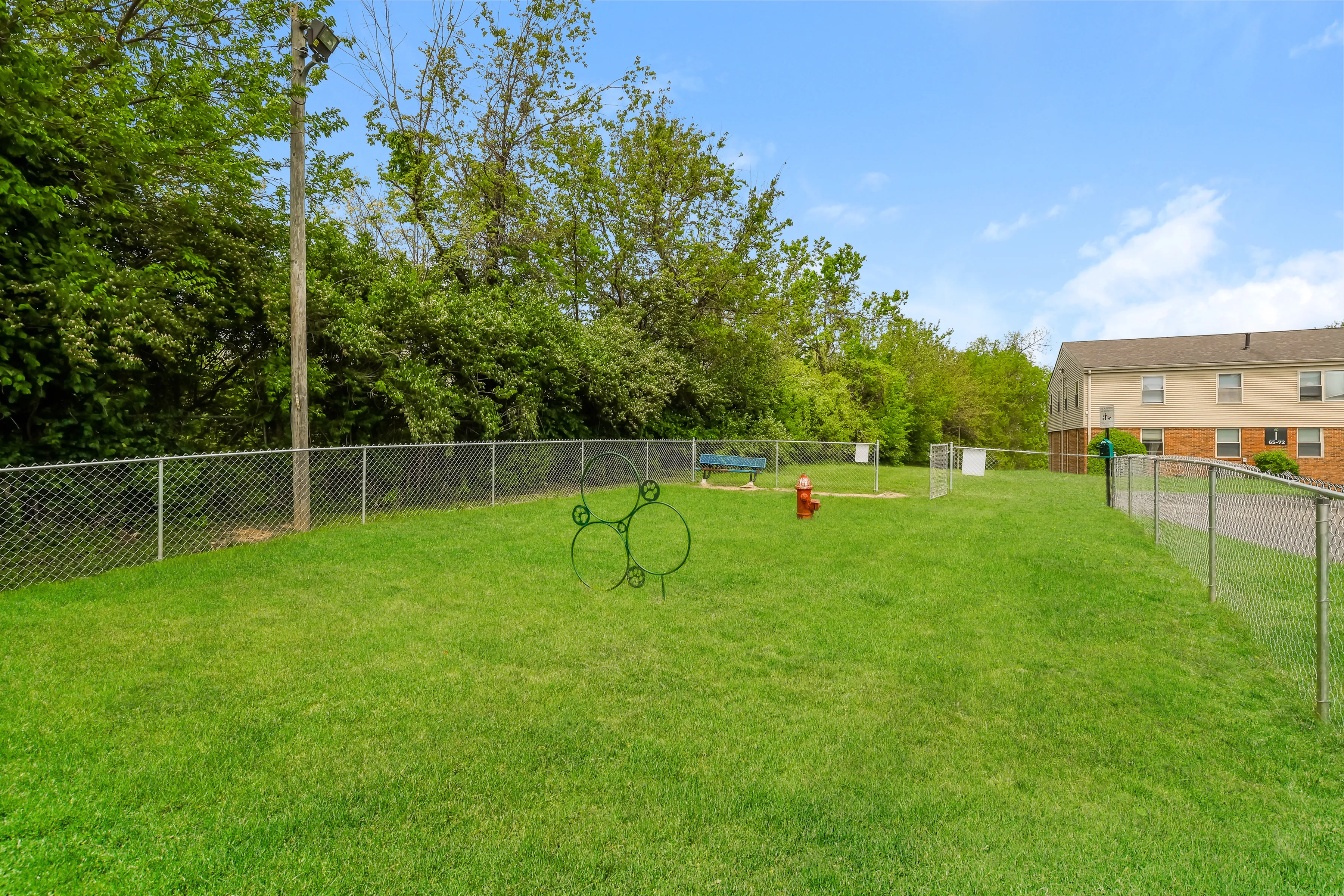 Charming fenced green space featuring a vibrant lawn, mature trees, and a quaint bench perfect for relaxation.