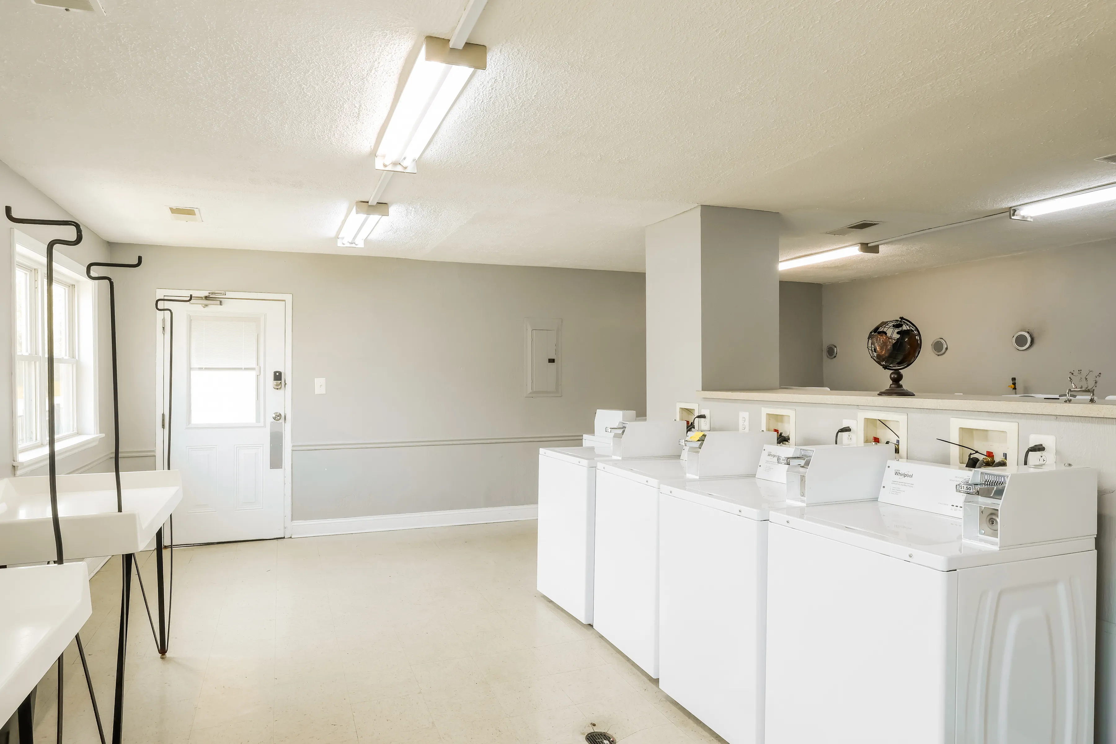 Bright and airy laundry room featuring multiple washers, abundant natural light, and ample space for convenience.