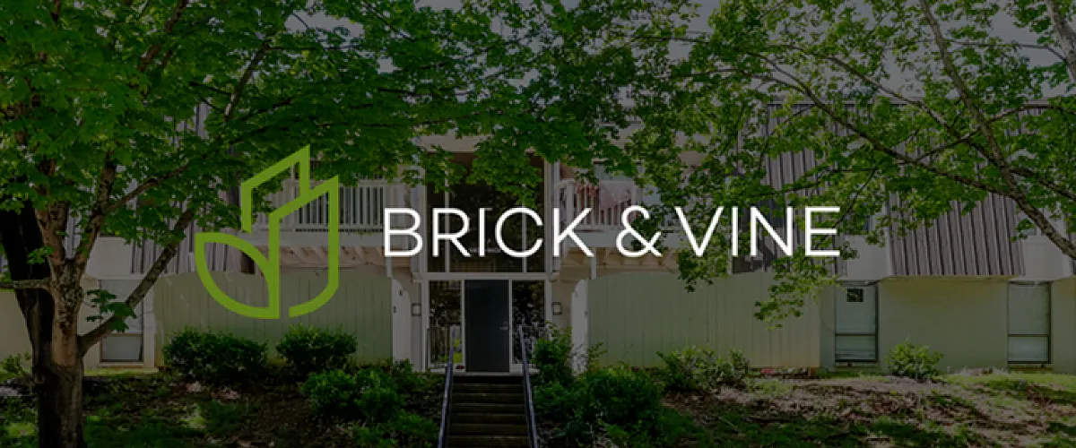 Charming Brick & Vine apartment exterior nestled among lush trees with a welcoming entrance.