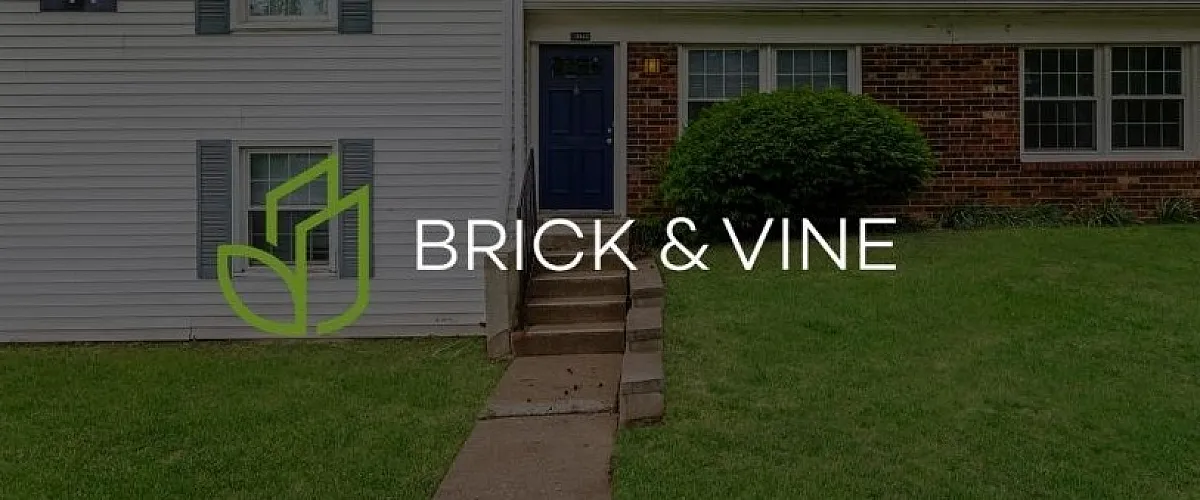 Charming duplex exterior with lush green lawn and inviting entrance at Brick & Vine Apartments.