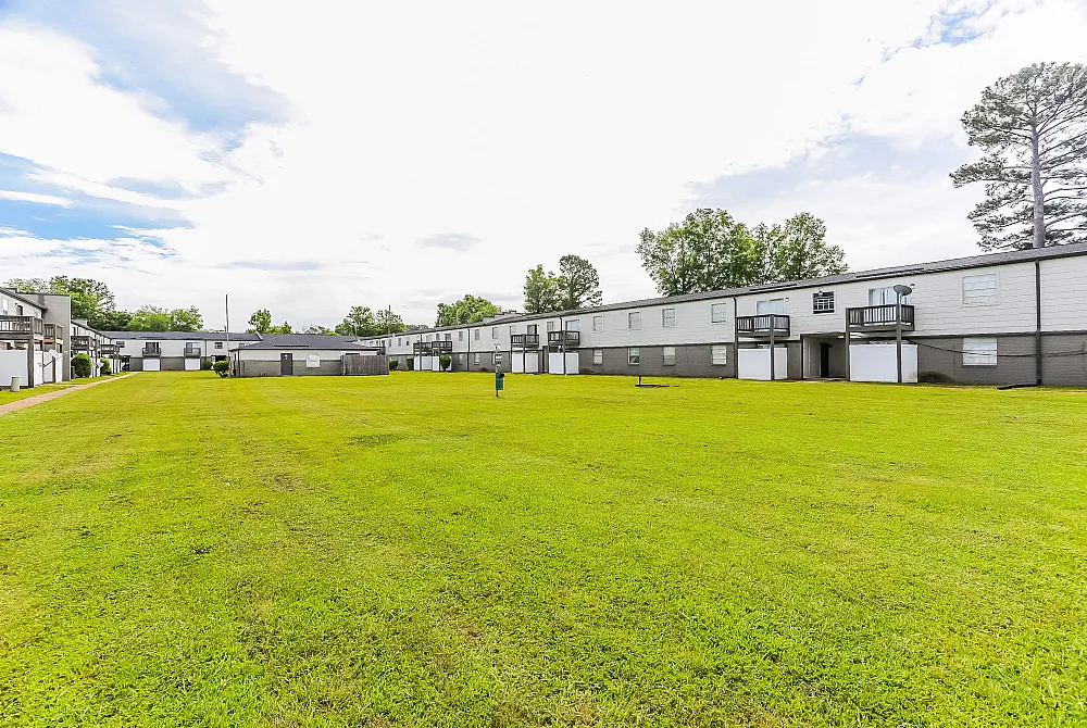 Vibrant courtyard-facing apartments with lush green lawns and surrounded by serene trees.
