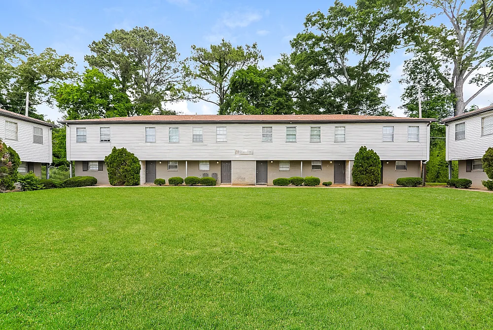 Charming townhouse complex showcasing well-maintained lawns, lush greenery, and a welcoming exterior, perfect for comfortable living.