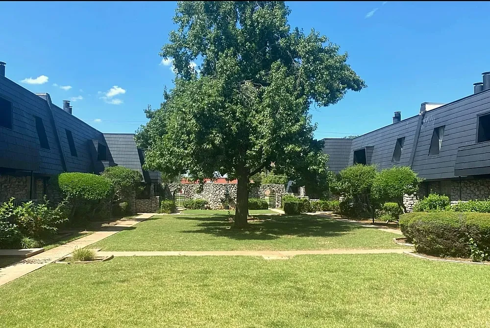 Charming apartment building nestled among lush greenery with inviting front steps, perfect for tranquil living.
