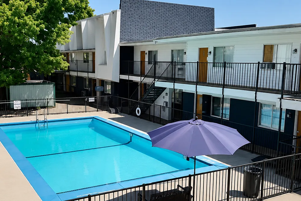 Modern apartment complex featuring a sparkling swimming pool, sunbathing area, and lush landscaping for ultimate relaxation.