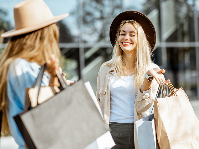 Joyful women enjoying a sunny shopping day with stylish hats and trendy bags.
