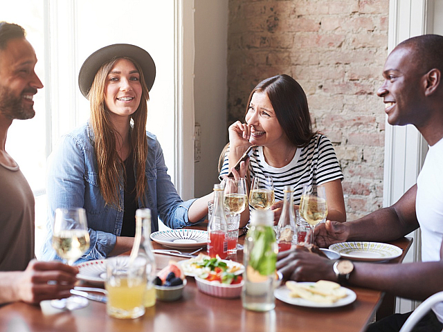 Vibrant dining experience with friends enjoying wine and conversation in a cozy, sunlit dining area.