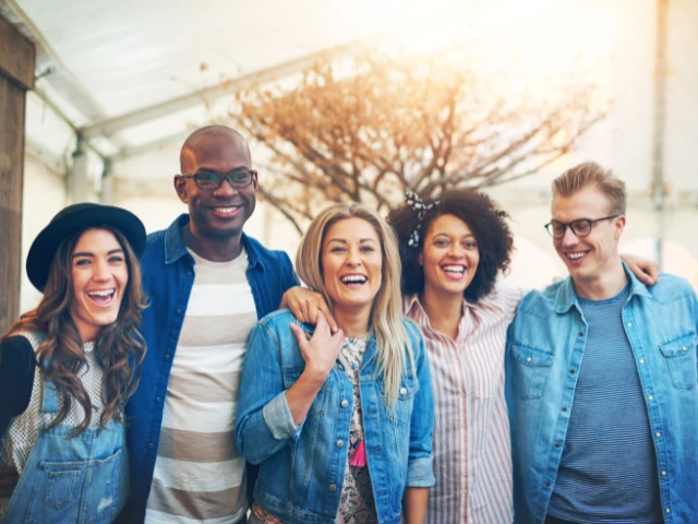 Group of five friends smiling and laughing together outdoors.
