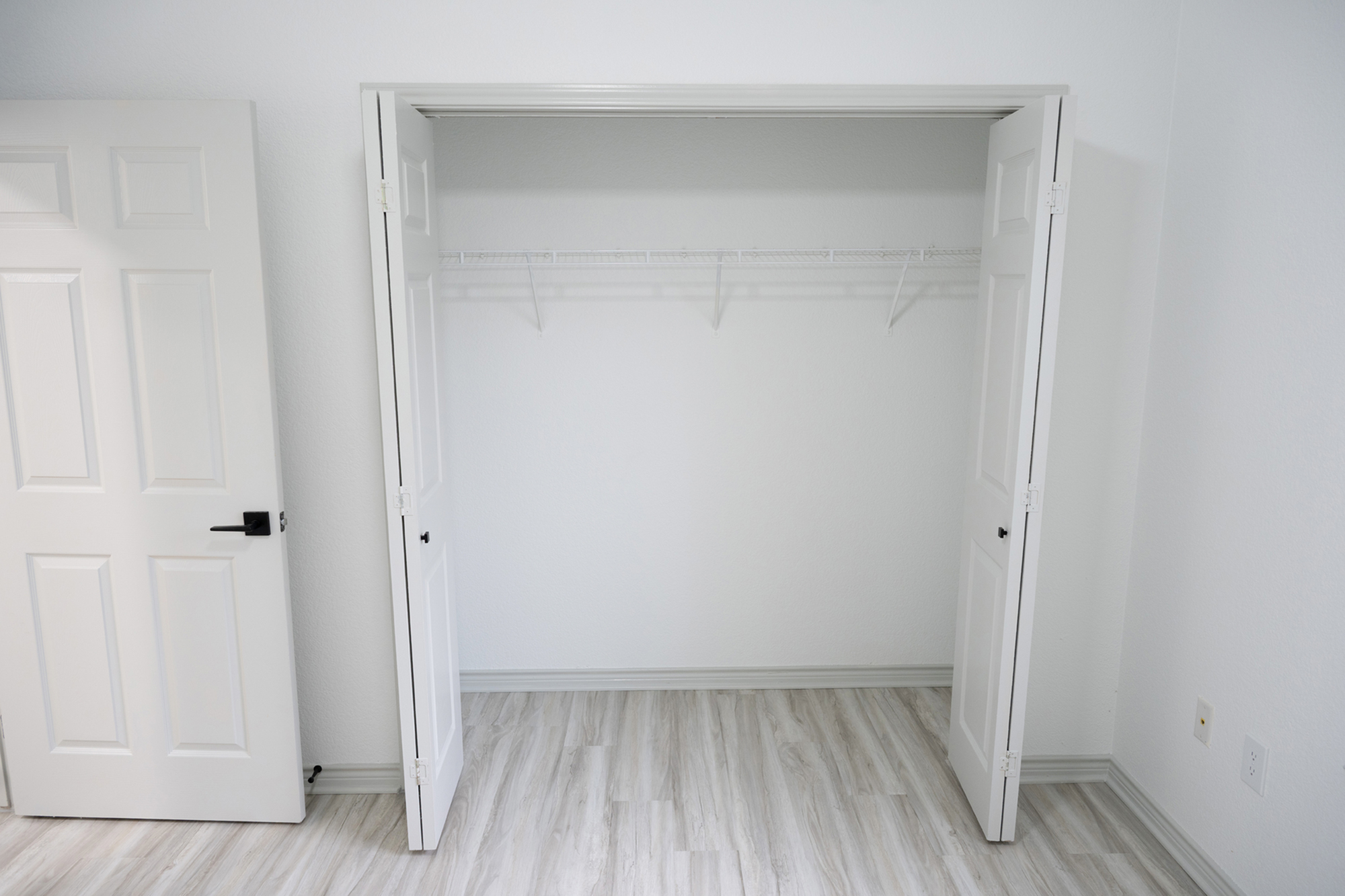 Sleek, spacious closet with double doors and modern flooring, perfect for organized living.