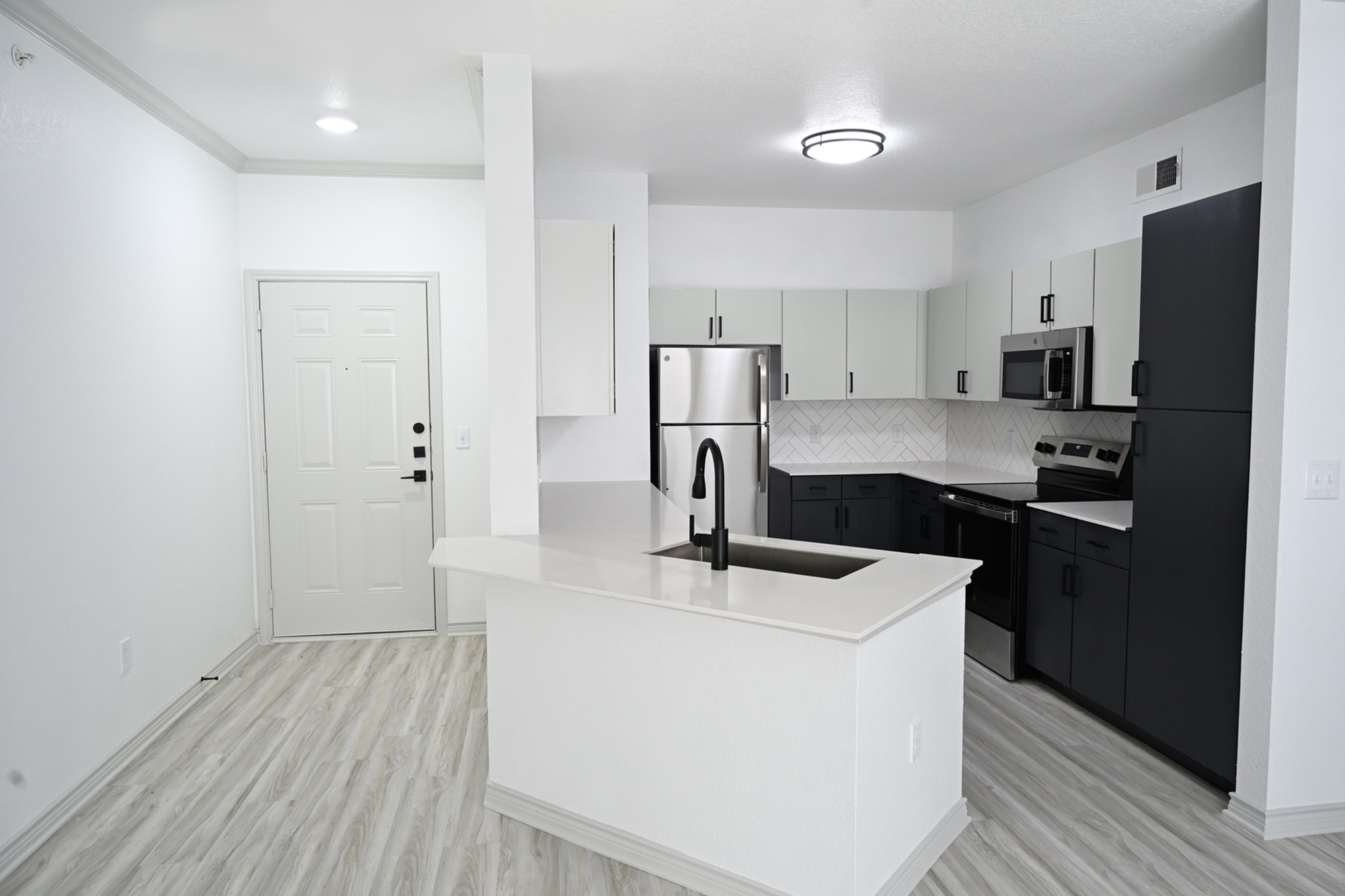 Modern kitchen design with sleek black and white cabinetry, stainless steel appliances, and elegant wood flooring.