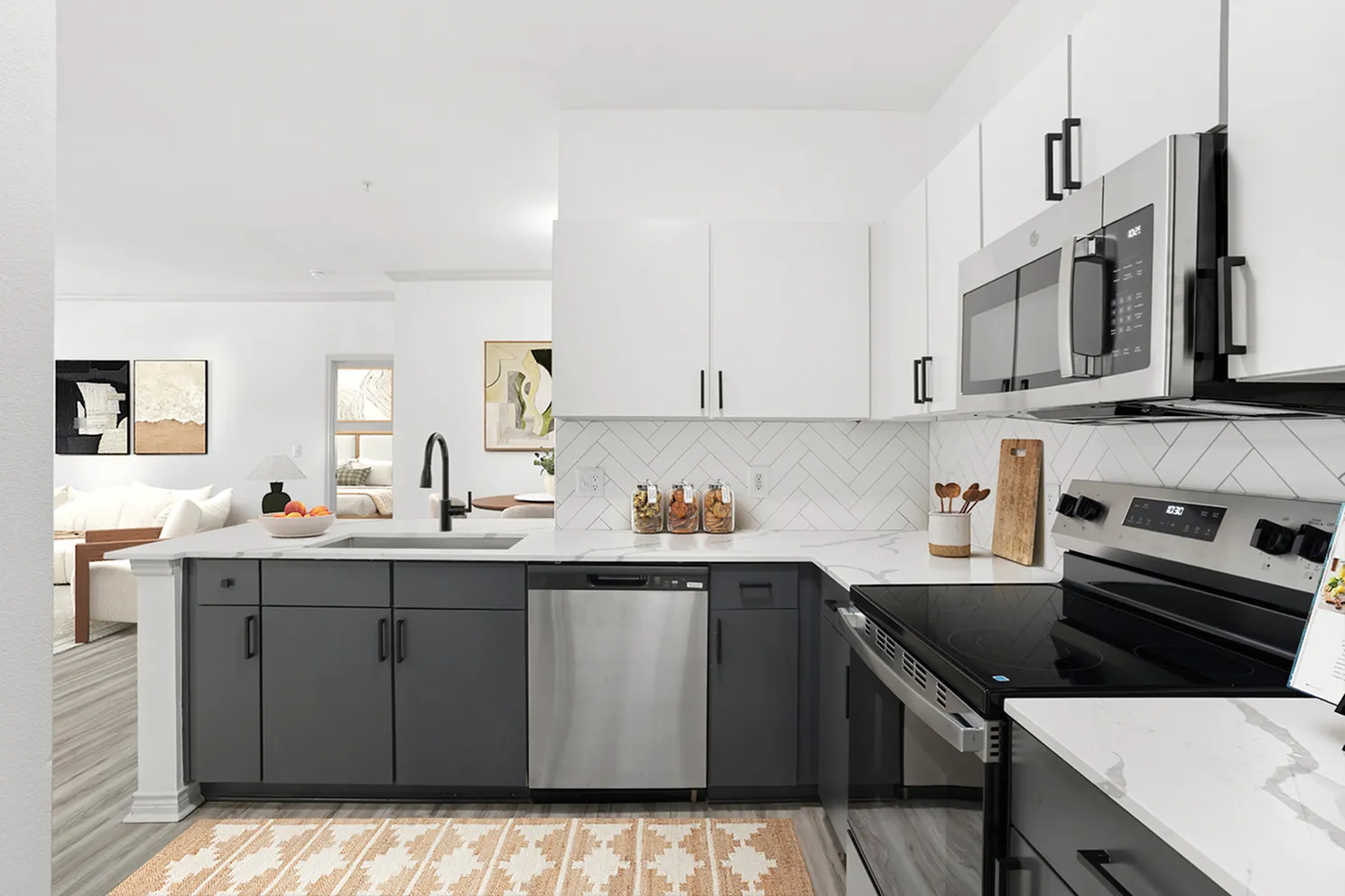 Modern kitchen with sleek white cabinetry, stainless steel appliances, and open access to a stylish living area, showcasing contemporary elegance.