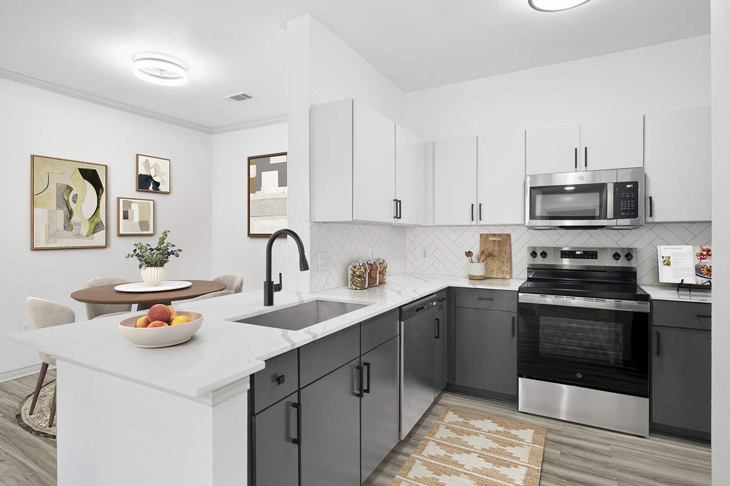 Modern kitchen with sleek white cabinets, stainless steel appliances, and elegant dining area, enhanced by stylish artwork and a chic faucet.