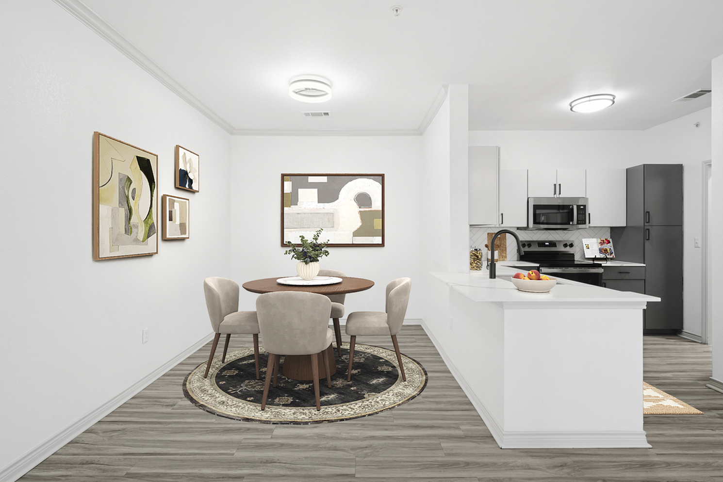 Modern apartment dining area with elegant round table, stylish chairs, and contemporary artwork, adjacent to a sleek, fully-equipped kitchen with stainless steel appliances.