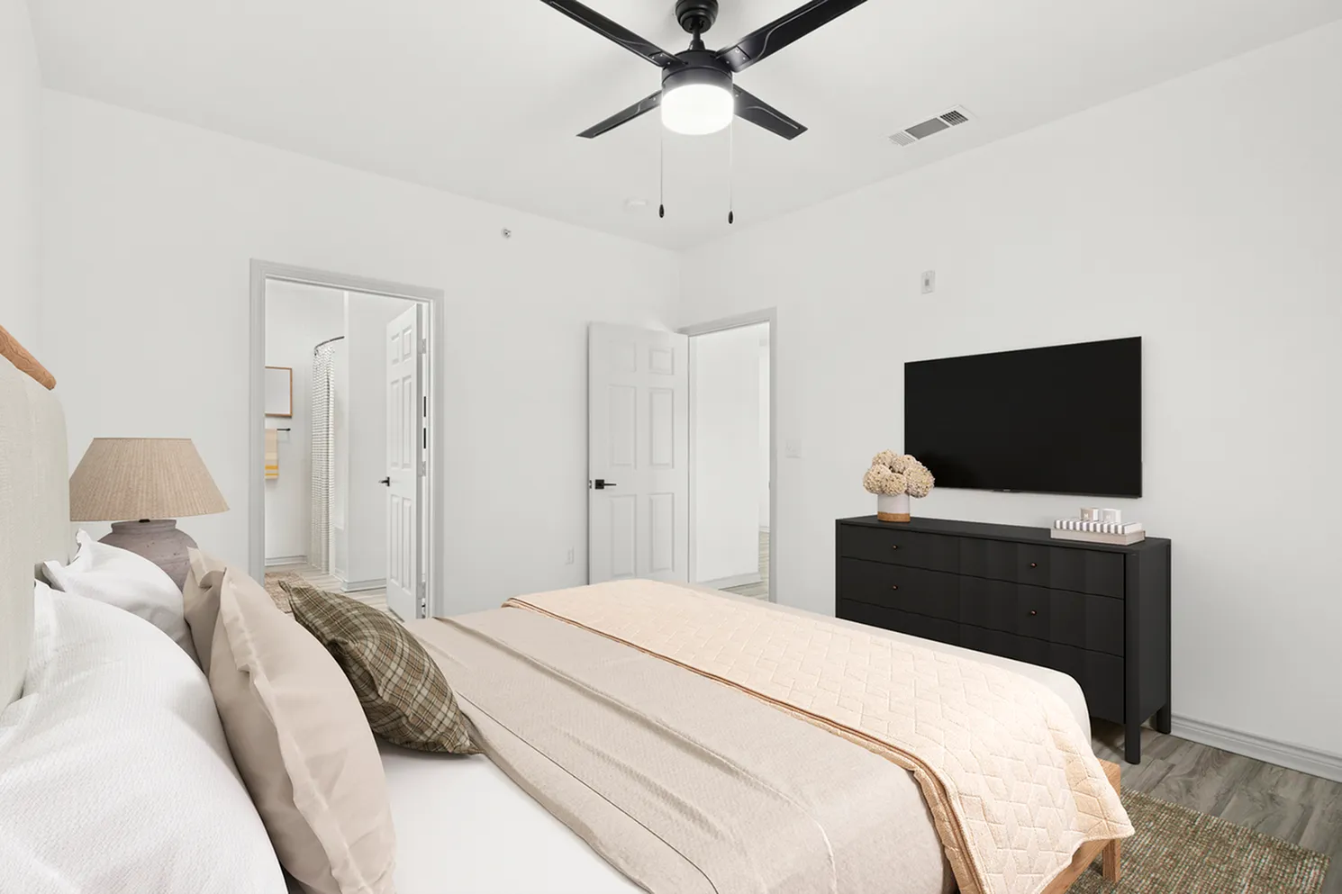 Elegant bedroom showcasing a modern ceiling fan, cozy bed with soft pillows, stylish dresser, and a sleek flat-screen TV on the wall.