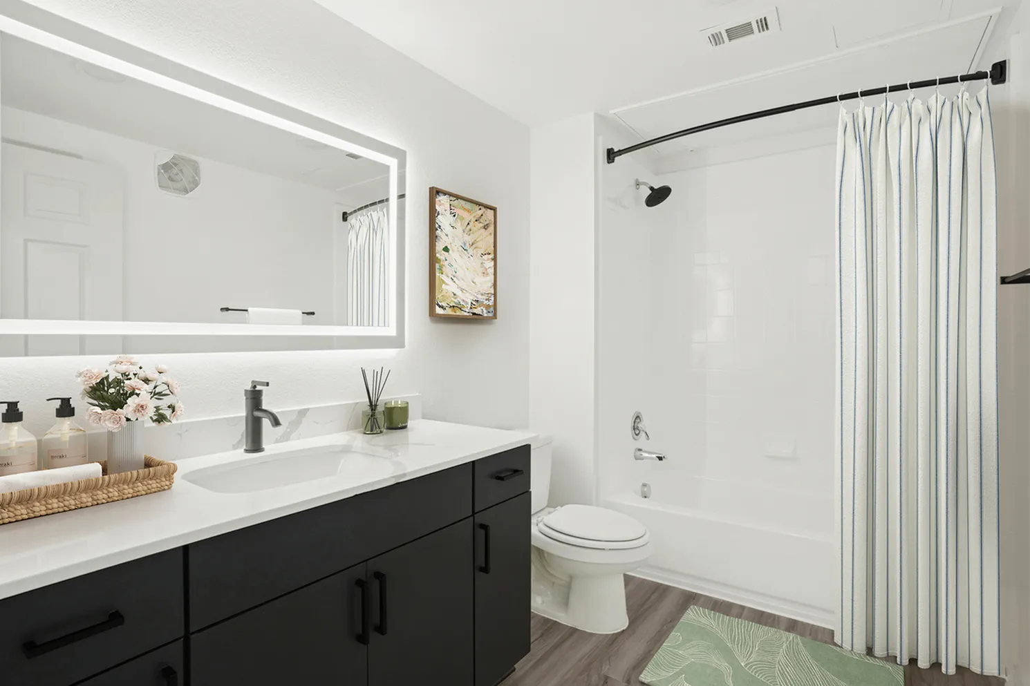 Modern bathroom featuring elegant lighting, sleek black vanity, and a bright, inviting tub with white shower curtain.