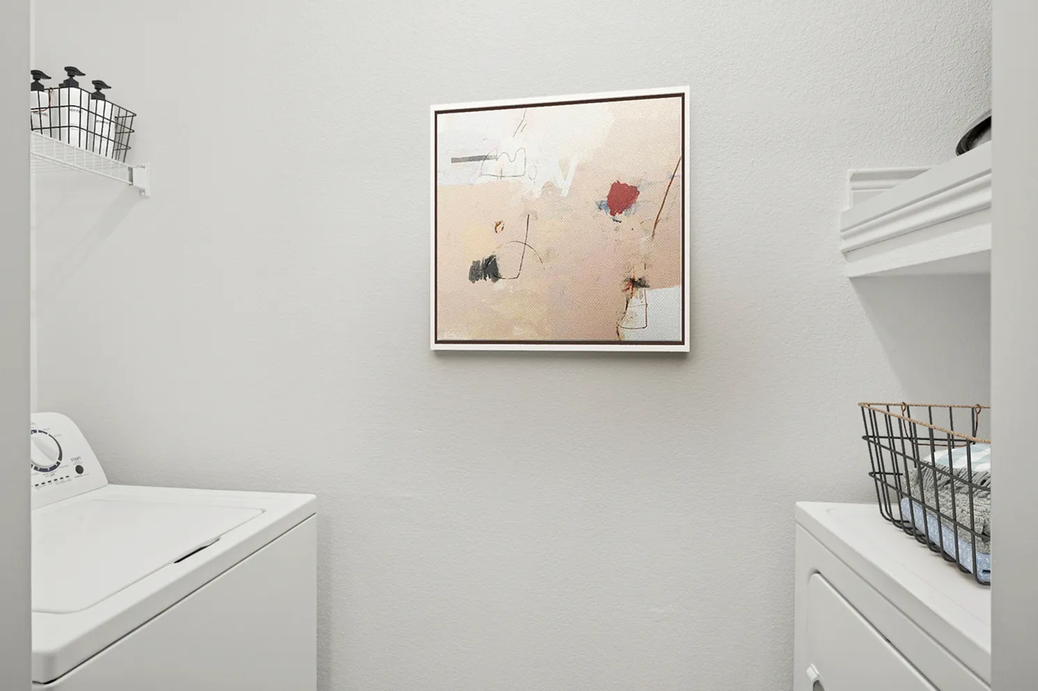 Contemporary laundry room featuring a modern washer and dryer, artistic wall decor, and sleek storage solutions.