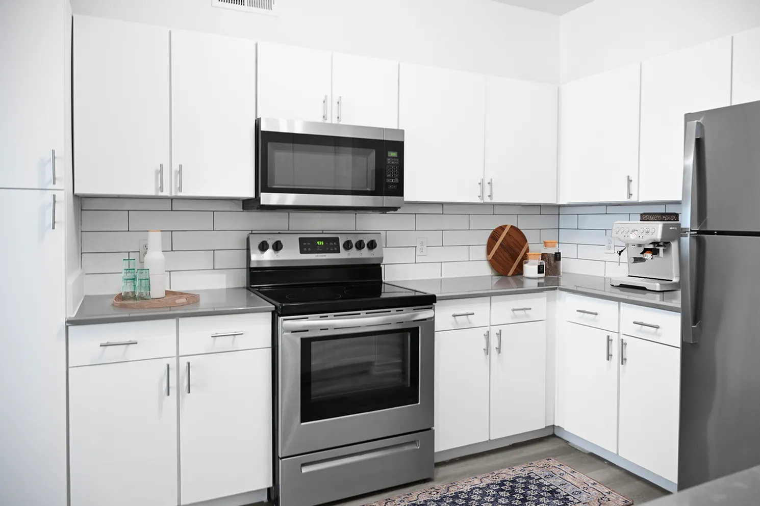 Modern kitchen with sleek white cabinetry, stainless steel appliances, and stylish subway tile backsplash.